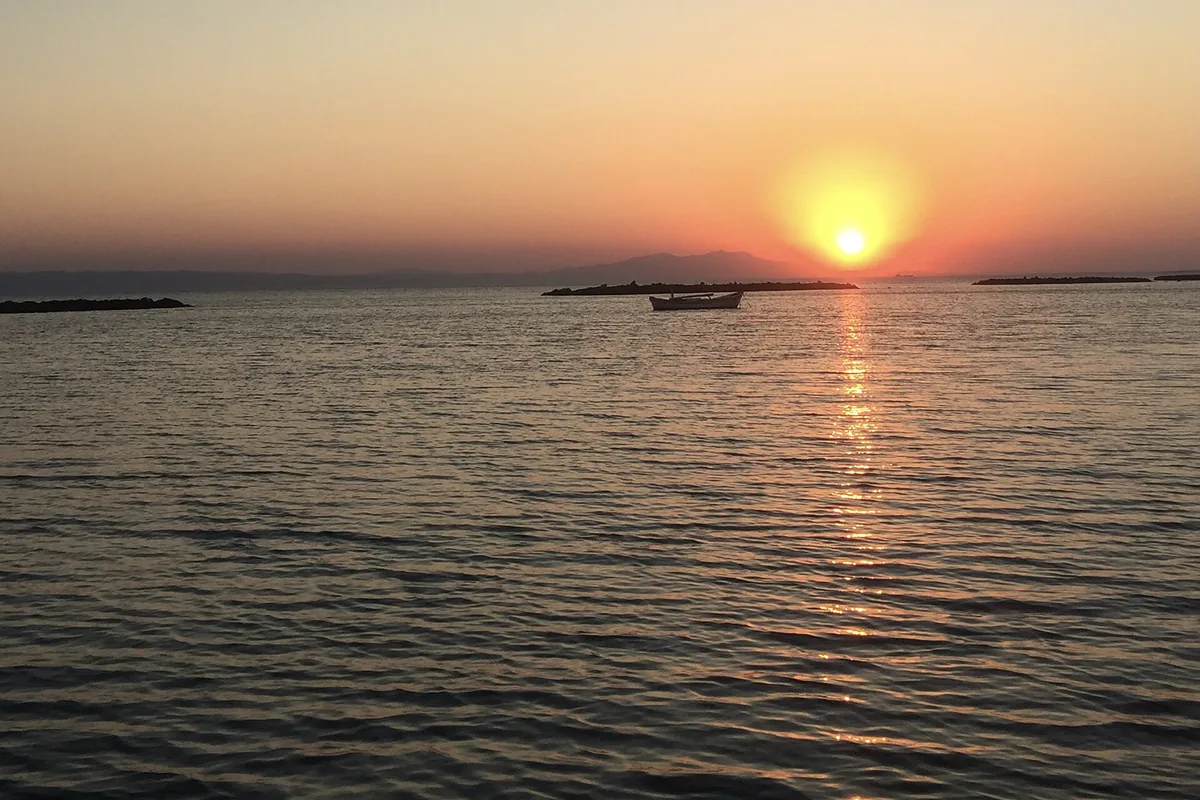 Altınova kıyısında gün batımı, sakin deniz ve uzakta tekneler