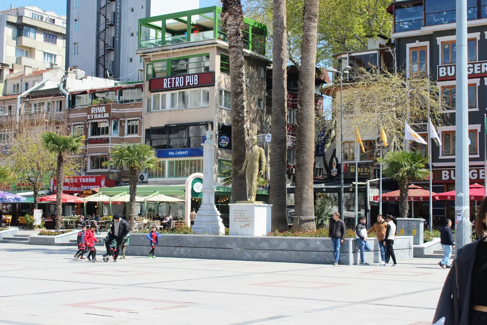 Bandırma Cumhuriyet Meydanı'nda Türk bayraklarıyla süslenmiş alan, Atatürk heykeli ve çevresindeki kafeler