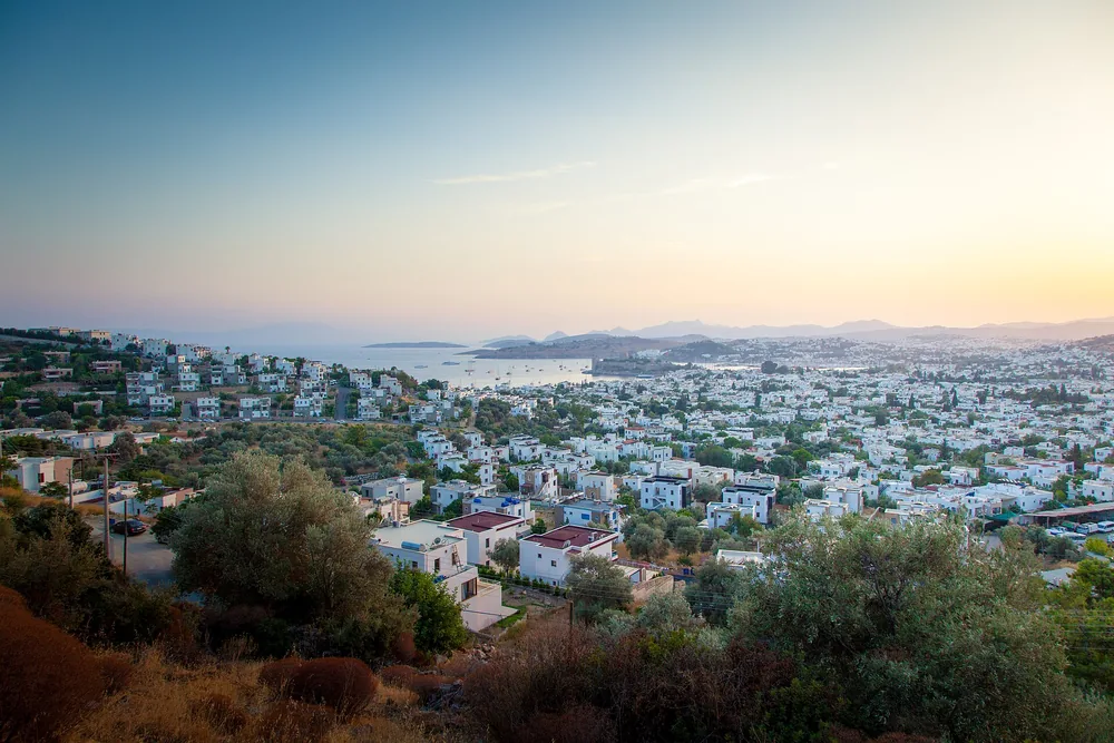 Bodrum koyunda akşam ışıklarının suya yansıması, önde küçük bir kayık
