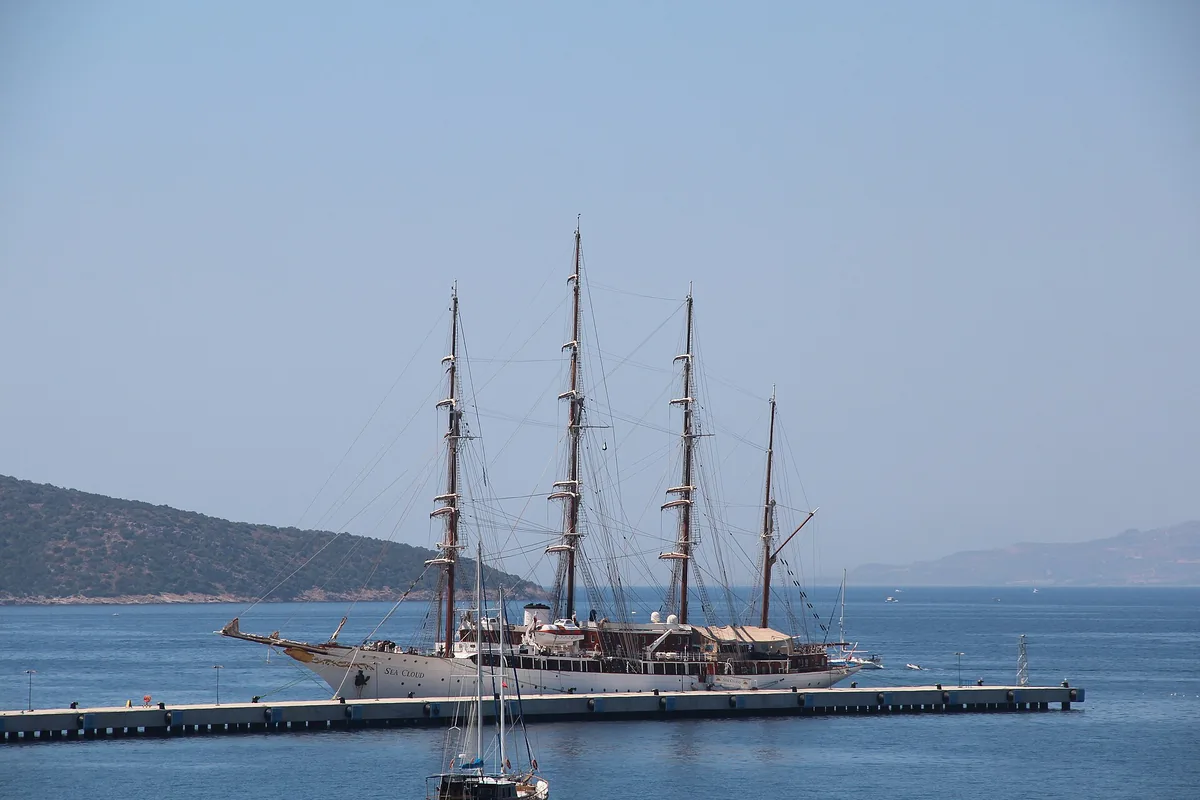 Bodrum açıklarında demirlemiş üç direkli yelkenli ve arkada yarımada silüeti