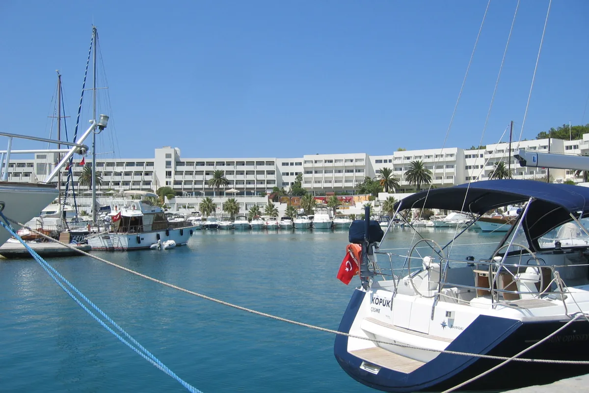 Çeşme Altınyunus koyunda bağlı tekneler ve arka planda kıyı yapılaşması