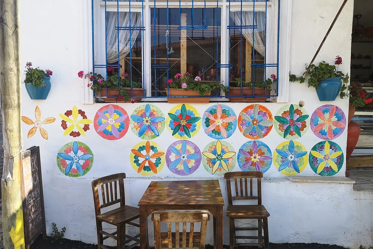 Germiyan'da taş ev cephesinde renkli tabak ve mandala motifleriyle süslenmiş avlu