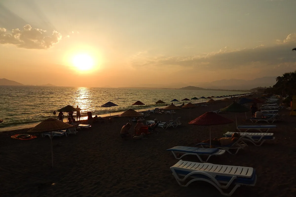 Çalış Plajı'nda gün batımı, şezlonglar ve şemsiyeler