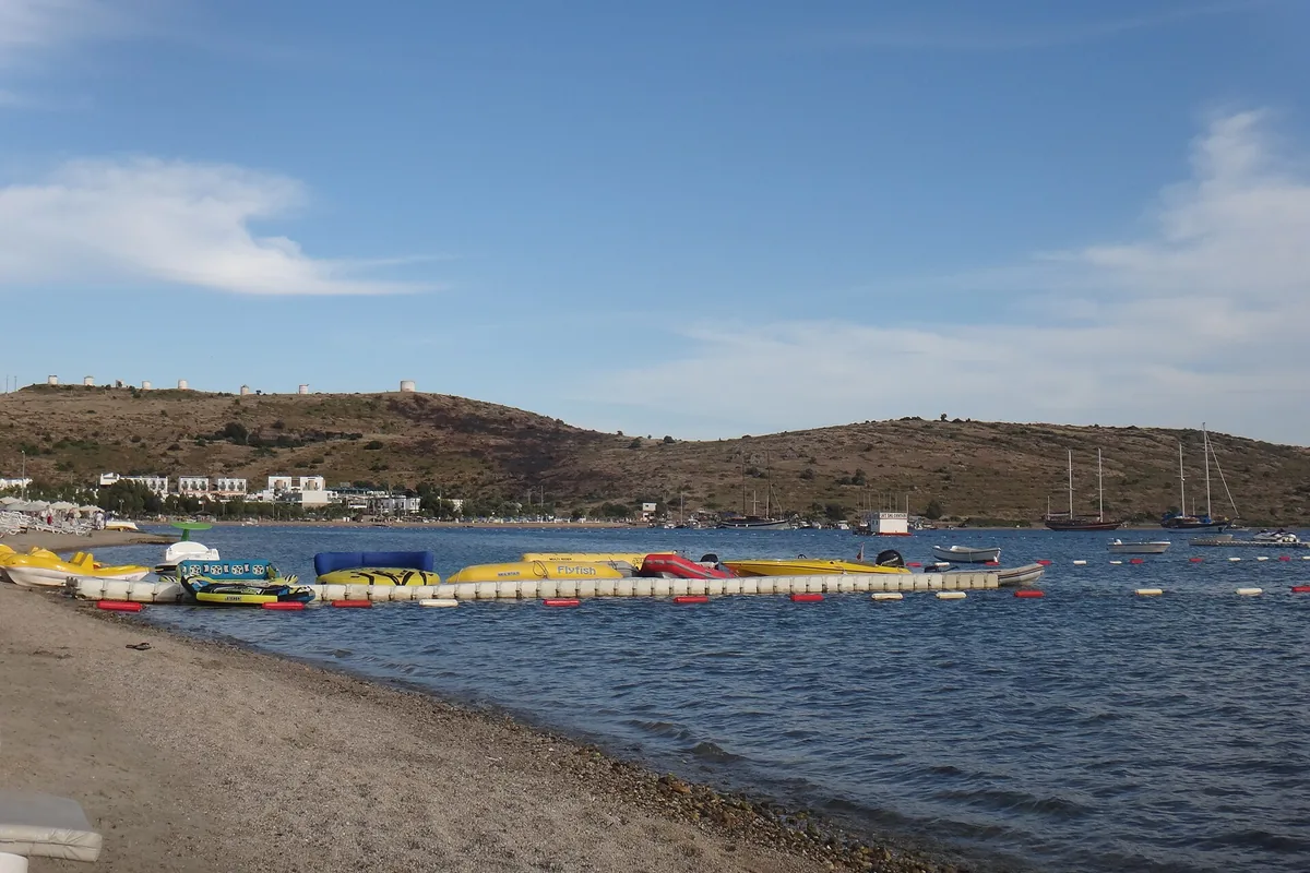 Gümbet sahilinde su üzerinde şişme bot ve deniz bisikletleri, arka planda tekneler