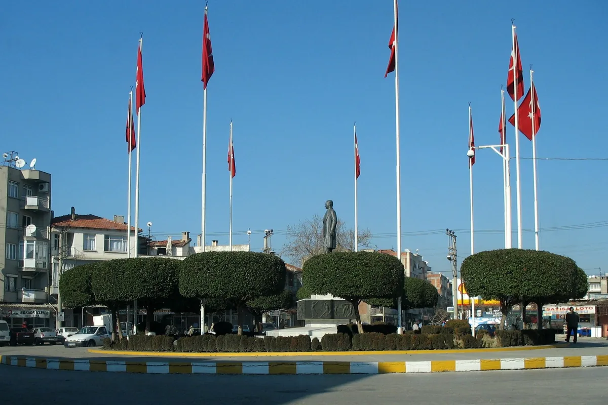 Akhisar şehir merkezindeki meydanda Atatürk Anıtı, Türk bayrakları ve düzenli ağaçlar