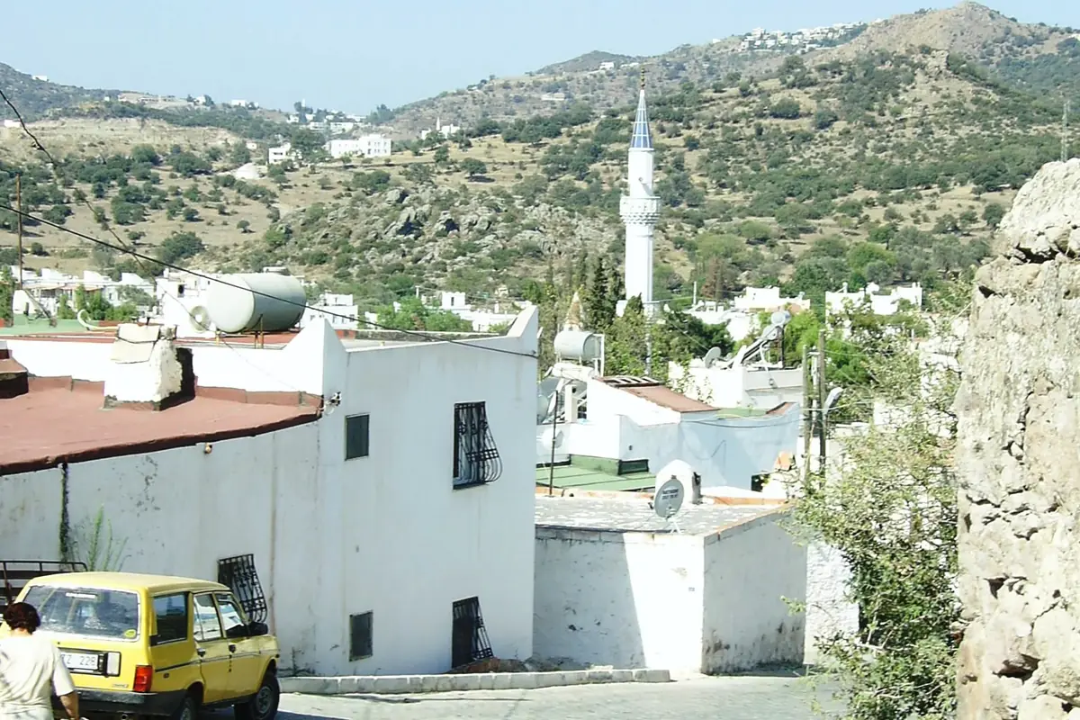 Ortakent köyünde taş evler, dar sokak ve arkada minare
