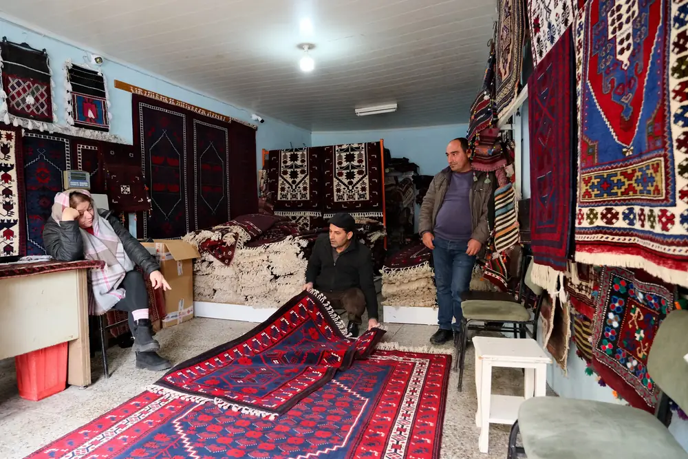Sındırgı'da bir halı dükkanının içinde Yağcıbedir halısı sergileyen dokumacı ve müşteriler