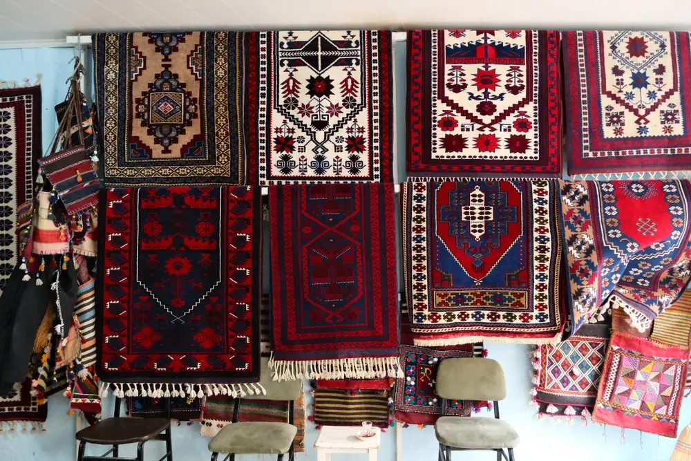 Sındırgı Yağcıbedir Yörük dokumacılarının el dokuması, lacivert-kırmızı-beyaz desenli halı ve kilim koleksiyonu duvarda sergileniyor